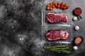 Vacuum packed Raw New York striploin beef steak, on black dark stone table background, top view flat lay, with copy space for text Royalty Free Stock Photo