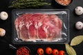 Vacuum packed serrano ham, on black dark stone table background, top view flat lay Royalty Free Stock Photo