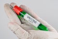 Vacuum tube with a sample of Covid-19 vaccine of green color in the hand with a medical glove Royalty Free Stock Photo