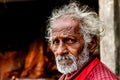Vadodara, 30 september 2018: close up portrait headshot of old indian ermit sadhu with sad red eyes and grey hair walking