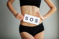 Vaginal or urinary infection and problems concept. Young woman holds paper with SOS above crotch. Royalty Free Stock Photo