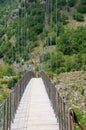 VAGLI SOTTO, LUCCA, ITALY AUGUST 8, 2019: Woman crossing suspension pedestrian bridge over Vagli Lake near Vagli di
