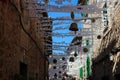 Sun protection and wicker products suspended between houses on a narrow street in the city of
