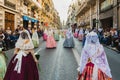 Valencia, Spain - March 17, 2019: Fallera Commission parading down Calle de la Paz, seen from behind, during the Fallas offering