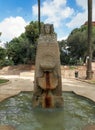 Monument bust on a high trapezoidal pedestal in the center of a small pool dedicated to the lady of Elche