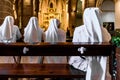 Valencia, Spain - September 25, 2019: Group of Christian nuns with white robes praying in a church