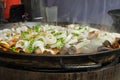 Valencian rice dish, seafood paella being cooked in a large shallow pan .