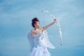 Valentin teenager girl with bow arrow ready to shoot. Angel teen with feathers wings on sky. Valentines Day. Royalty Free Stock Photo