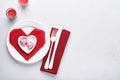 Valentinas day table setting white color with white silverware, red napkin folded as heart, candles, champagne, glasses on white