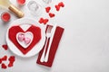 Valentinas day table setting white color with white silverware, red napkin folded as heart, candles, champagne, glasses on white