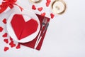 Valentinas day table setting white color with white silverware, red napkin folded as heart, candles, champagne, glasses on white