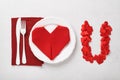 Valentinas day table setting white color with white silverware, red napkin folded as heart on white background for greetings. I