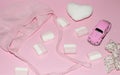 Valentine baby girl minimal pink background. Baby accessories: soft heart knitted hat sweets toy car and bow.Flat lay