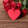 Valentine background of gift tag and red roses on wood. Space for copy Royalty Free Stock Photo