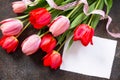 Valentine background or greeting card. Congratulatory sheet of paper with red and ÃÂ¿ÃÂ¸ÃÂ½ÃÂº tulips on a dark stone background.