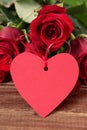 Valentine background of heart shape gift tag and red roses on wood Royalty Free Stock Photo