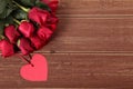 Valentine background of heart shape gift tag and red roses on wood. Space fo Royalty Free Stock Photo