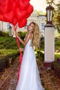 Valentine Beautiful girl with red balloons laugh, in the park. Beautiful happy young woman. Birthday party and bride at the