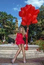 Valentine Beautiful girl with red balloons laugh, in the park. Beautiful happy young woman. Birthday party.