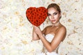 Valentine beautiful girl with red heart  on flowers background. Beautiful Happy Young woman in white elegant dress. Royalty Free Stock Photo