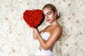 Valentine beautiful girl with red heart isolated on flowers background. Beautiful Happy Young woman in white elegant dress. Royalty Free Stock Photo