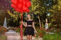 Valentine Beautiful young girl with red balloons laugh, in the park. Beautiful happy kid. Christmas party. Joyful little model