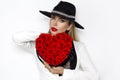 Valentine Beauty, elegant girl with red heart with roses. Portrait of a young female model with gift and hat. Royalty Free Stock Photo