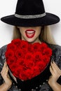 Valentine Beauty girl with red heart roses. Portrait of a young female model with gift and hat, isolated on background. Royalty Free Stock Photo