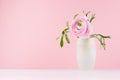 Valentine day background - gentle pink flower buttercup with green leaves in elegant vase on soft light white wood board.