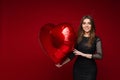 Valentine day celebrating young girl with heart balloon on red background with blank space for advertising