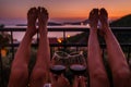 Valentine day concept image of legs of persons drink wine at the sea view balcony at sunset