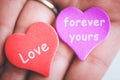 Valentine day concept. Red decorative heart with love inscription and purple heart with inscription forever yours in female hands. Royalty Free Stock Photo