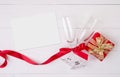 Valentine day concept, wineglass and red ribbon and gift box with greeting card on white wooden table background. Royalty Free Stock Photo