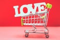 Valentine day concept from word love in shopping trolley on red paper background Royalty Free Stock Photo