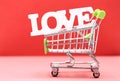 Valentine day concept from word love in shopping trolley on red paper background Royalty Free Stock Photo