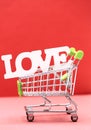 Valentine day concept from word love in shopping trolley on red paper background Royalty Free Stock Photo