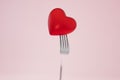 Valentine& x27; day dinner. a red heart pricked on a fork on a pink background. 3D render