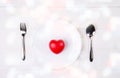 Valentine day, heart shape on dish and utensil with bow for dinner on wooden table, spoon and fork and plate on desk. Royalty Free Stock Photo