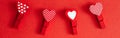 Valentine Day holiday. Four cute little small clothespins with pattern hearts on red background. Romantic dating love. Valentine