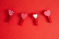 Valentine Day holiday. Four cute little small clothespins with pattern hearts on red crimson background with copyspace. Romantic