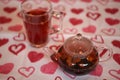 Valentines day drink photography image of a glass teapot and cup filled with hot apple spice flavor tea on love heart cloth