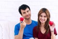 Valentine day. Love and relationships concept. smile young couple sitting on white couch holding red heart in their hands Royalty Free Stock Photo