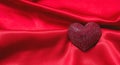 Valentine day red color ruby heart shaped jewel on empty red silk fabric background. Copy space Royalty Free Stock Photo