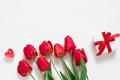 Valentine Day Romantic Background. Red tulips, a gift with a bow, and candle hearts on a white background with copying space. Flat