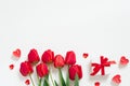 Valentine Day Romantic Background. Red tulips, a gift with a bow, and candle hearts on a white background with copying space. Flat Royalty Free Stock Photo