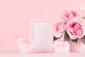 Valentine days decor and gift in soft light pastel pink color - romance bouquet of roses, heart, gift box, blank frame on wood. Royalty Free Stock Photo