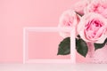 Valentine days mockup with blank frame for text and design - romance bouquet of roses and wooden pink frame on white wood table.