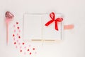 Valentine flatlay. Blank diary, pink heartshaped pen feathers on white background. Notebook mockup, cute girlish style