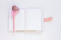 Valentine flatlay. Blank diary, pink heartshaped pen feathers on white background. Notebook mockup, cute girlish style