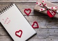 Valentine gift box, notebook and red heart shape tag on wooden b Royalty Free Stock Photo